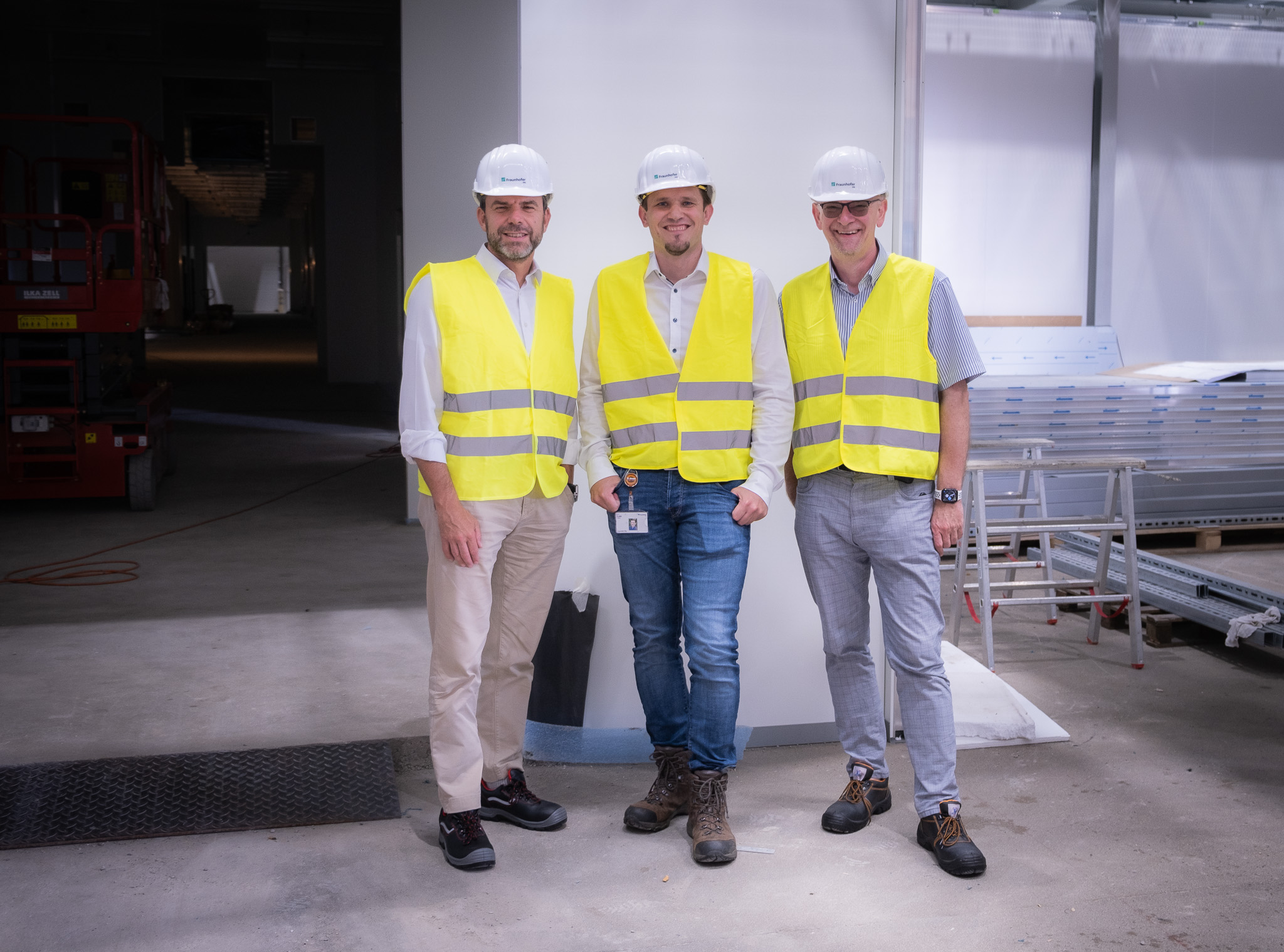 The three battery researchers Dr. Pieter Jansens, Prof. Dr. Simon Lux and Prof. Dr. Martin Winter visit the construction site of the FFB PreFab. The group photo shows them in front of the entrance to a clean and dry room.